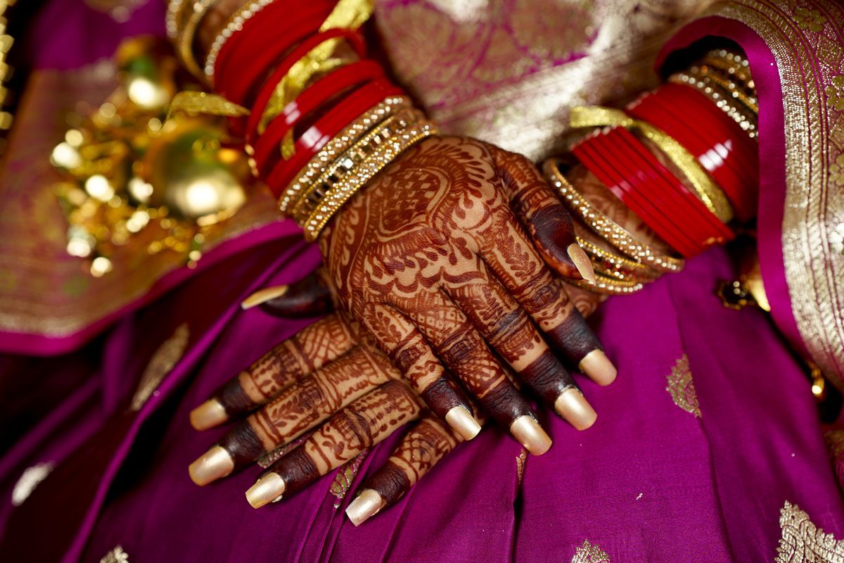 Bridal mehndi design on hands with red bridal bangles